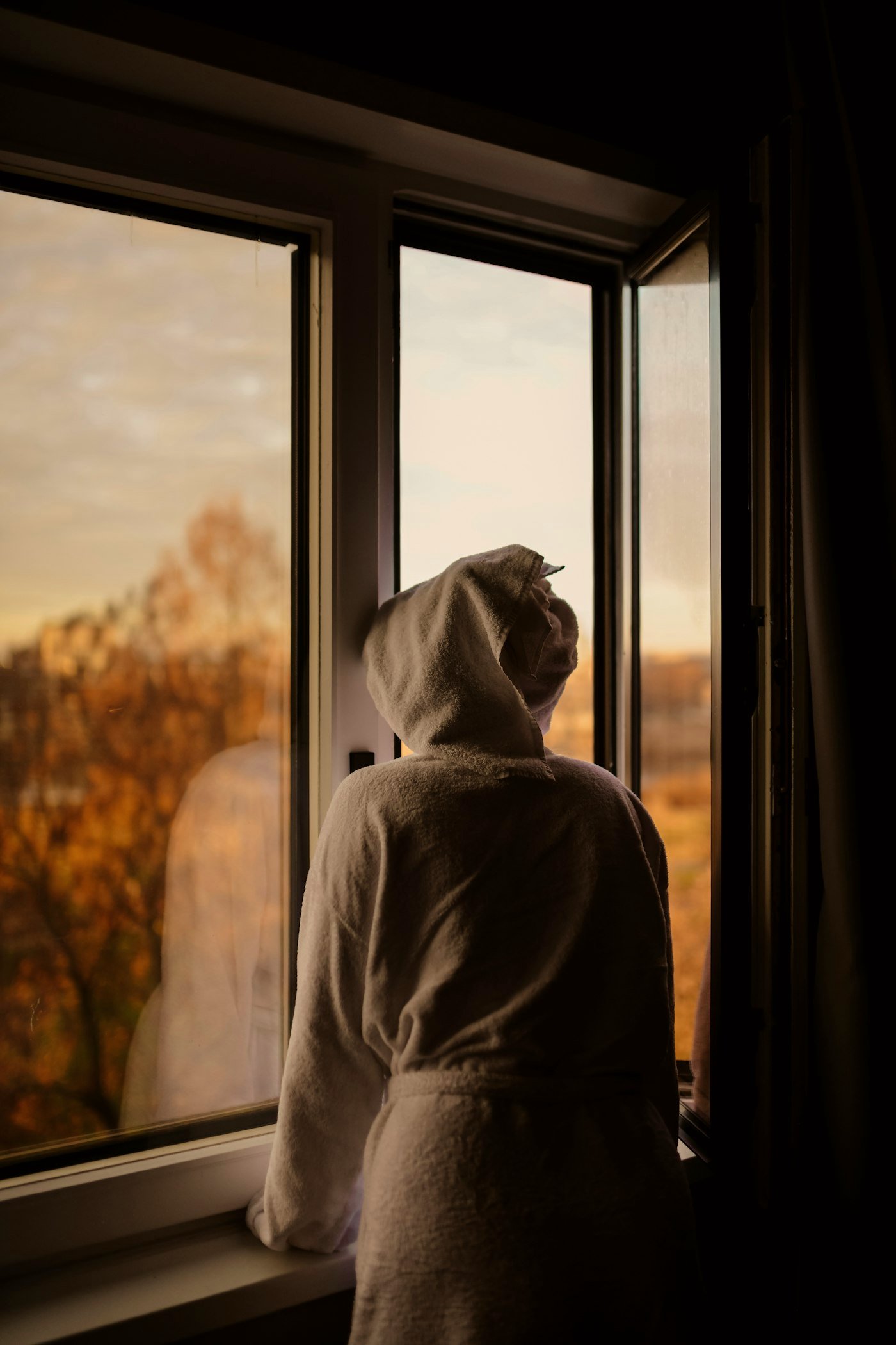 Eine Gestalt am Fenster im Licht der goldenen Stunde